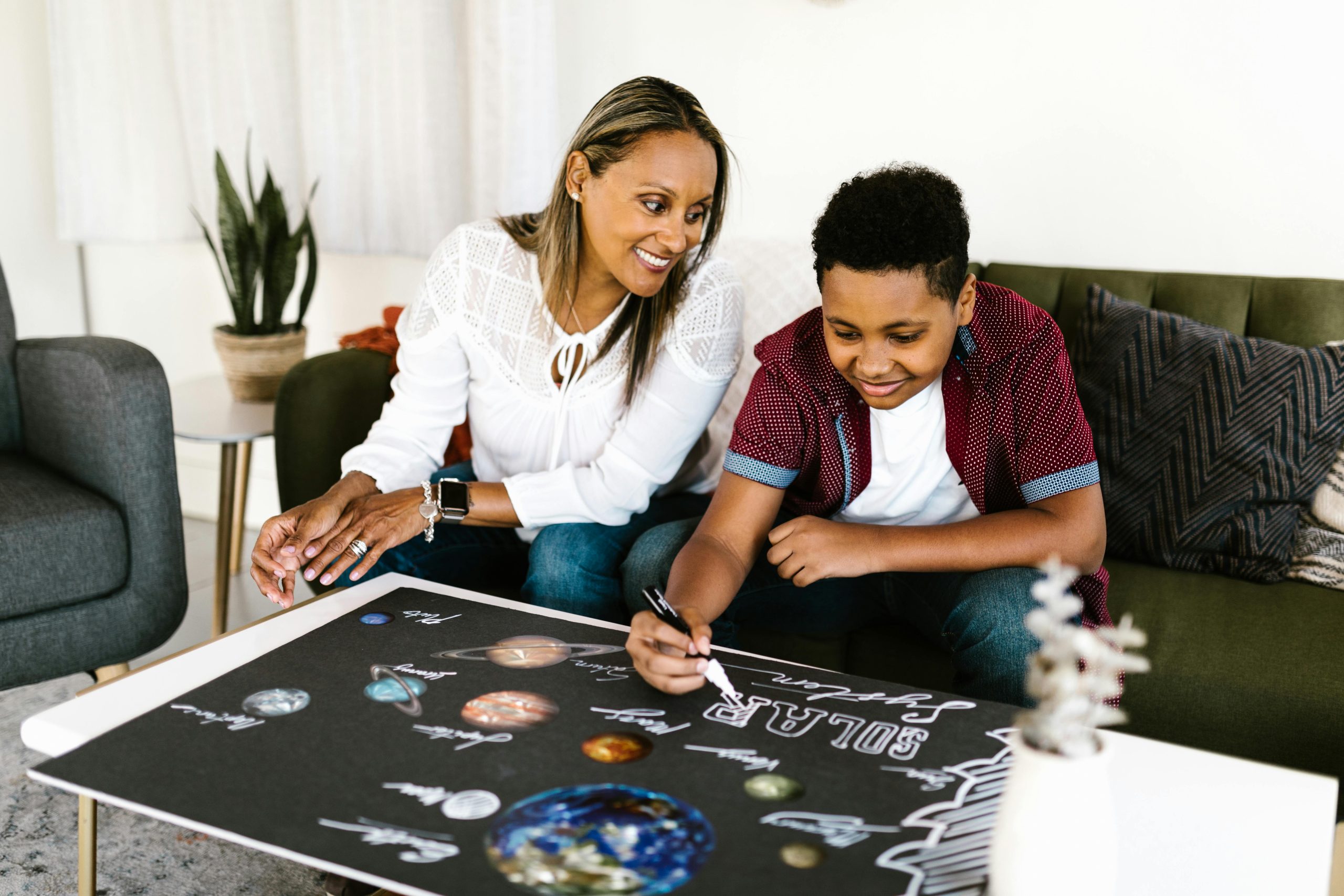 Mother and son engaging in a creative school project about the solar system at home.